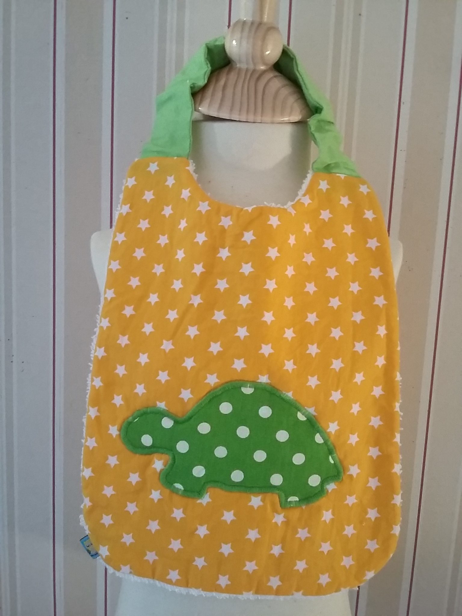 Bavoir à étoiles blanches sur fond jaune, avec appliqué motif tortue à pois blancs sur fond vert : 12 €