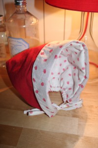 Petit béguin taille 12 mois en velours milleraies rouge 100% coton. Intérieur en tissu coton à petites fraises. Doublure en ouatine légère pour plus de chaleur. Lavage 30Â° en machine. Ne pas repasser le velours sur l'endroit.