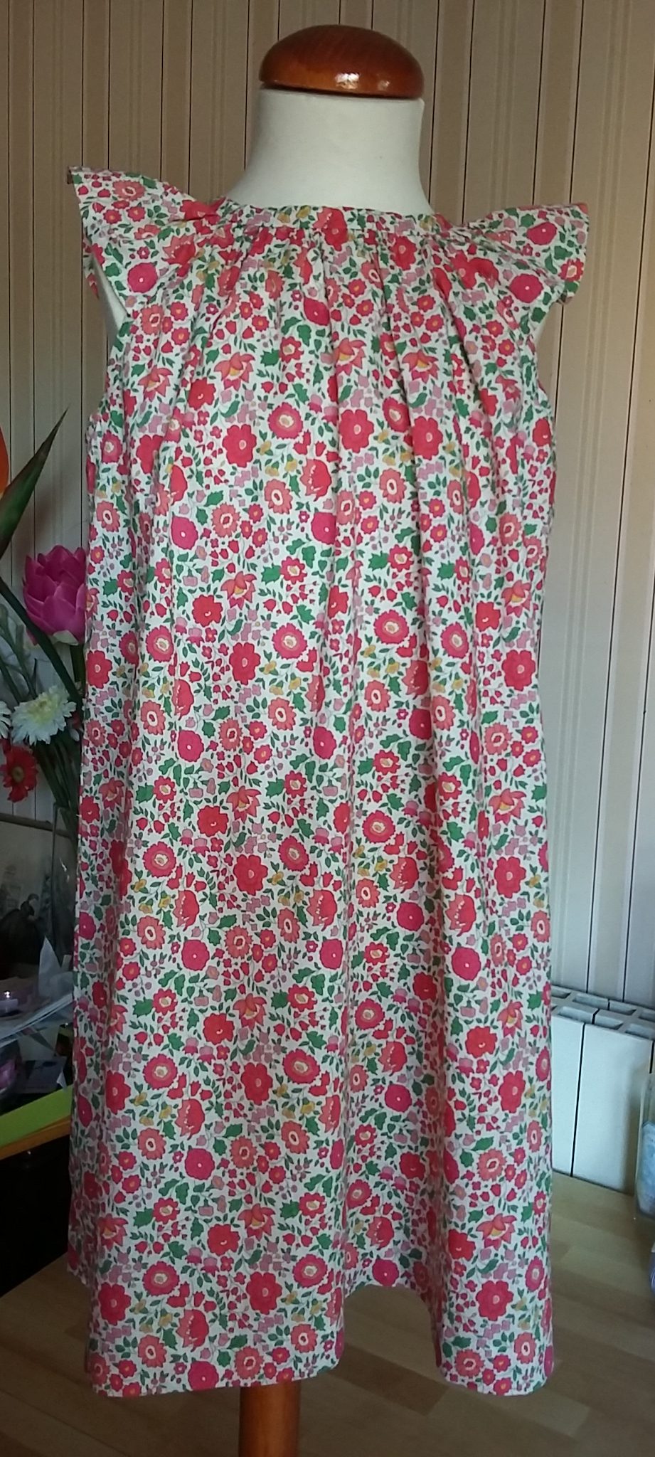 Robe 100% coton en Liberty D'Anjo rouge/rose. Taille 6 ans. Manche volantée. Légèrement froncée au col. Fermeture dos par crochet.