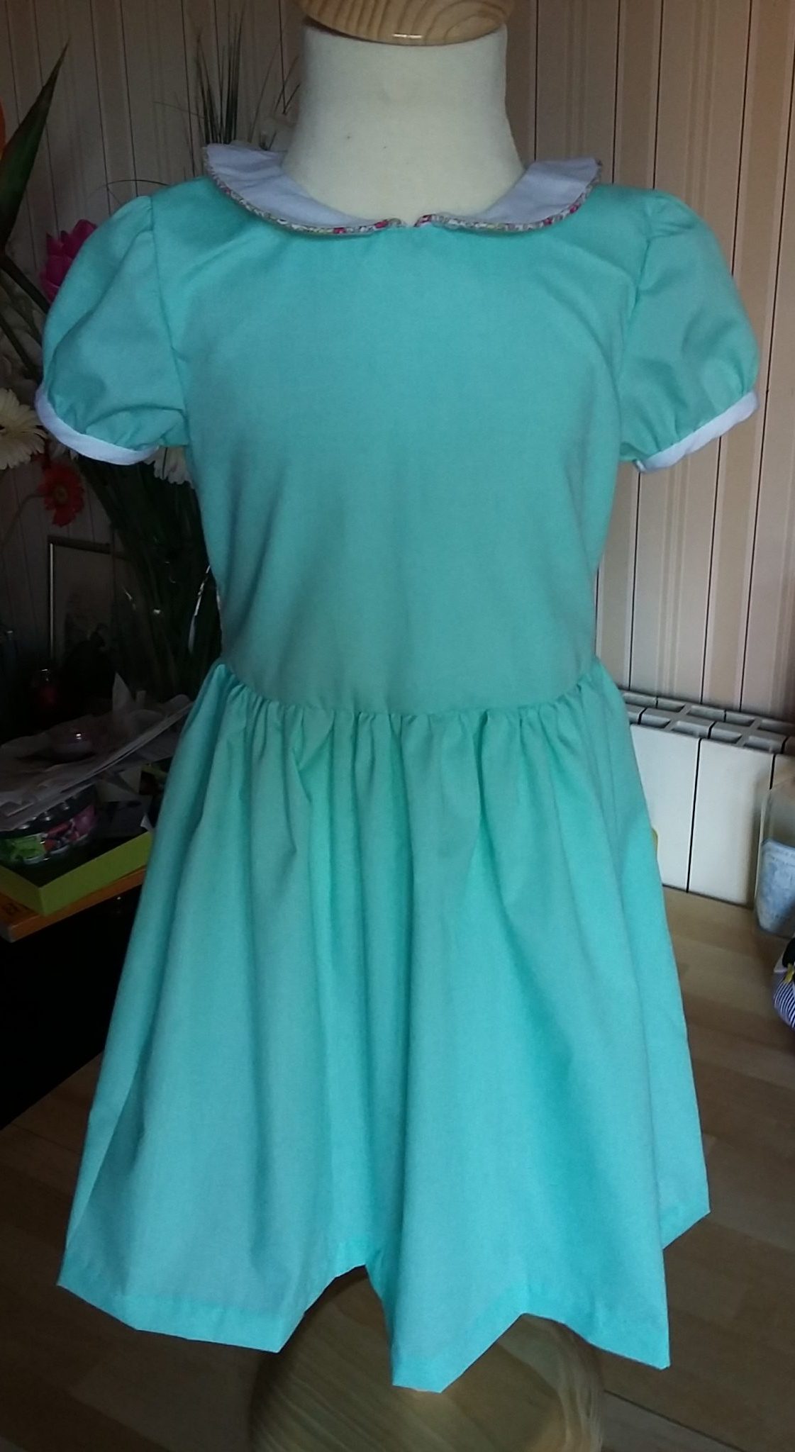 Robe 100% coton couleur vert d'eau. Taille 4 ans. Col et bords de manches contrastant en piqué de coton blanc. Passepoil pour le col en Liberty Eloise rose. Ceinture dans ce même Liberty. Boutons en nacre blanche.