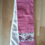 Écharpe en velours milleraies rose foncé (coton) avec bande de Liberty Felicité prune à chaque bout sur le recto. Verso en tissu doudou blanc agrémenté d'un passant permettant de maintenir l'écharpe serrée. Dimensions : 65 x 10 cm environ. Lavage 30Â° en machine. Ne pas repasser le velours sur l'endroit.